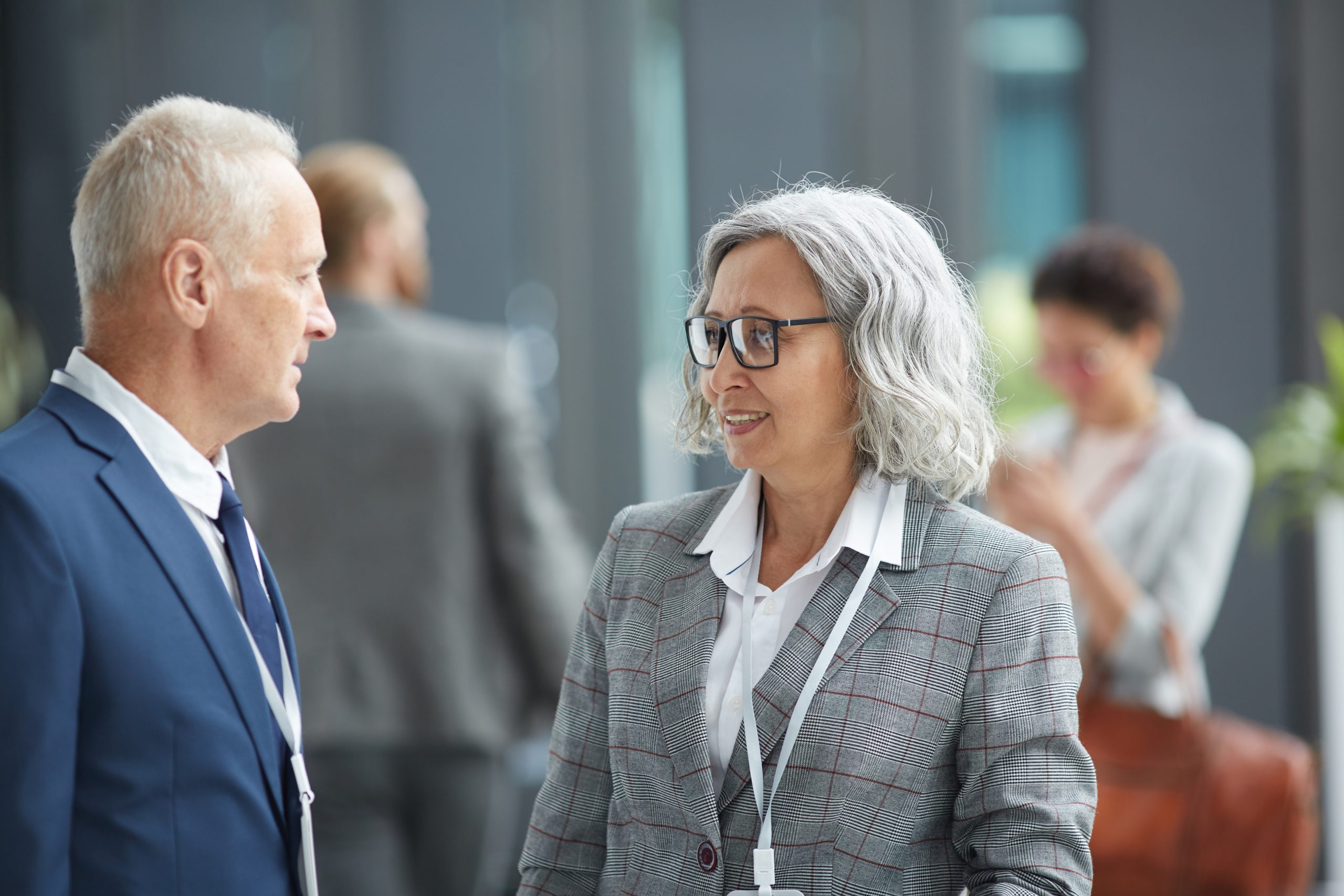 Older man and older women in the foreground of a diverse business event