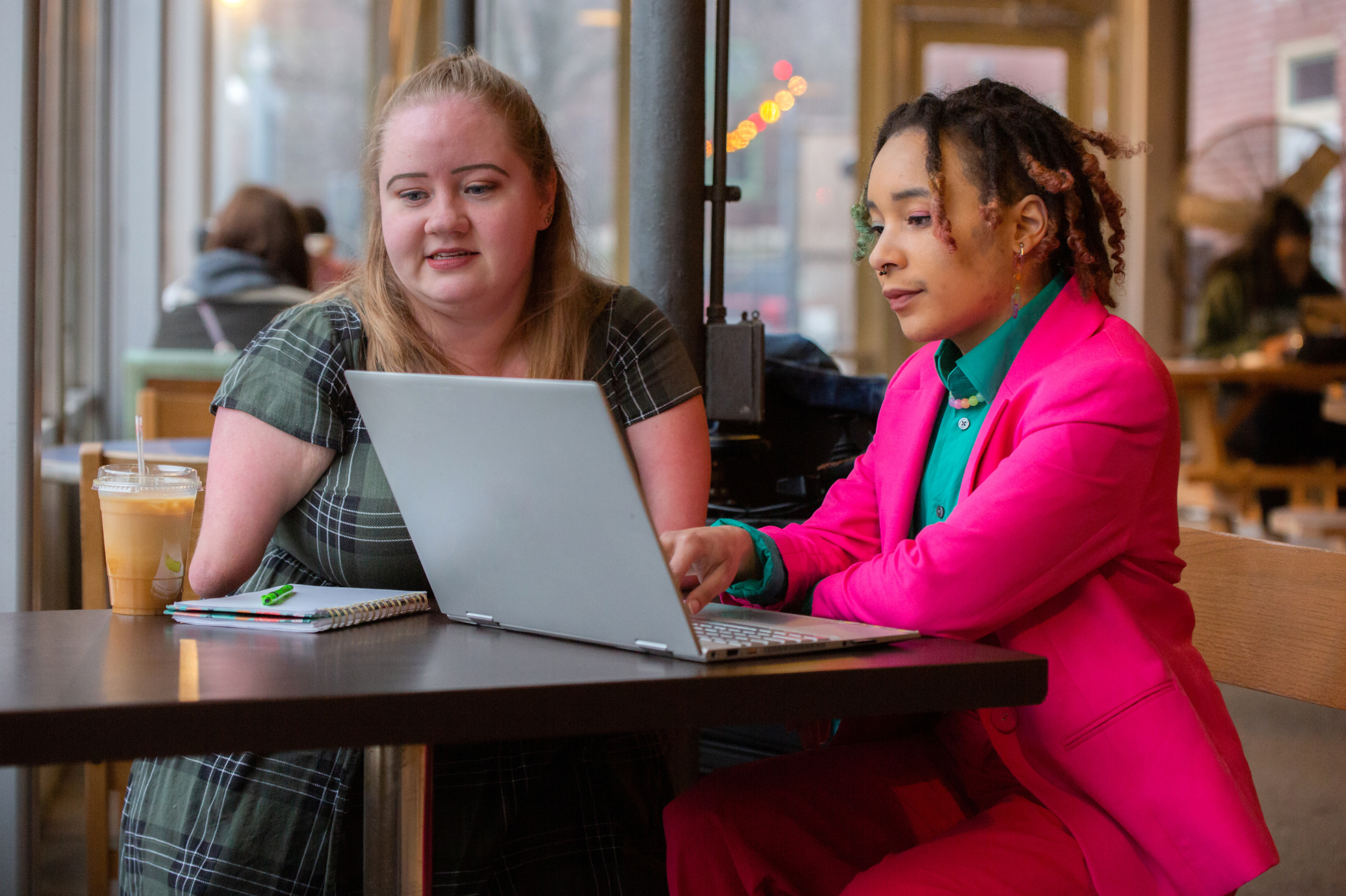 Two women planning at a laptop, one has a visible disability. one is a women of colour